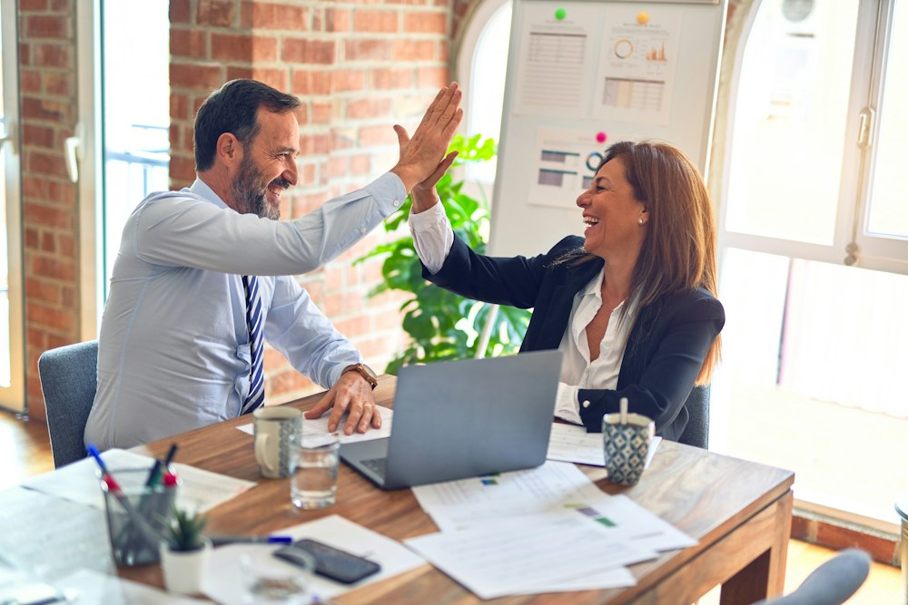 Two professionals celebrating at an office desk